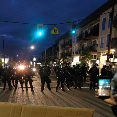 A protester records police in riot gear as they form a wall to push crowds of demonstrators in Portland, Ore., on June 30, 2020, in the wake the murder of George Floyd.