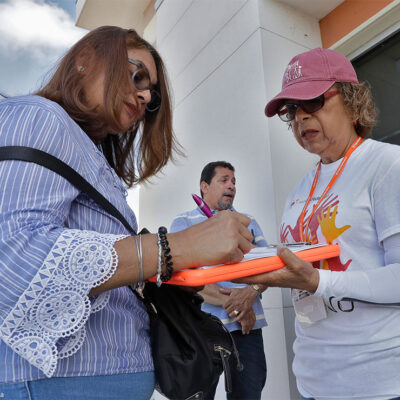 Canvasser Ana M. Vigo, right, registers a woman, left, to vote as a male bystander looks on outside the Polk County Tax Collectors office in Davenport, Fla.