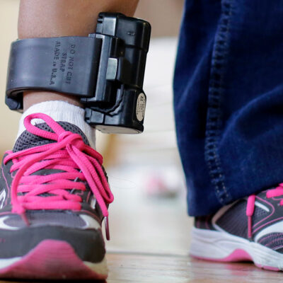 An individual wearing an ankle monitor.