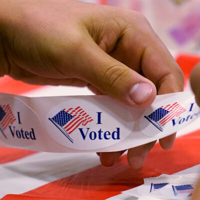 A volunteer prepares "I Voted" stickers at a polling station.
