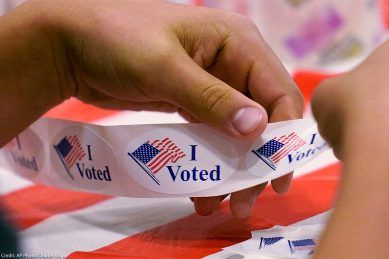 A volunteer prepares "I Voted" stickers at a polling station.