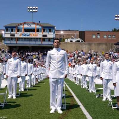 US Coast Guard cadets in white uniforms stand in neat rows at the commencement for the United States Coast Guard Academy in New London, Conn.