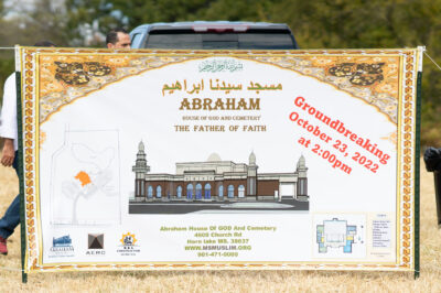 A sign advertising the groundbreaking of Abraham House of God Mosque & Cemetery, with a drawing of a mosque.