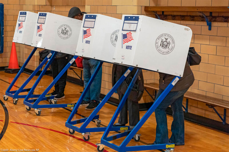 Four people, with their faces and bodies hidden behind voting privacy shields, are casting their votes for the midterm elections on Election Day November 08, 2081 in a New York City public school.