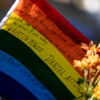 A waving rainbow flag reading "Rest In Power Daniel Aston" sits at the memorial created outside of Club Q.
