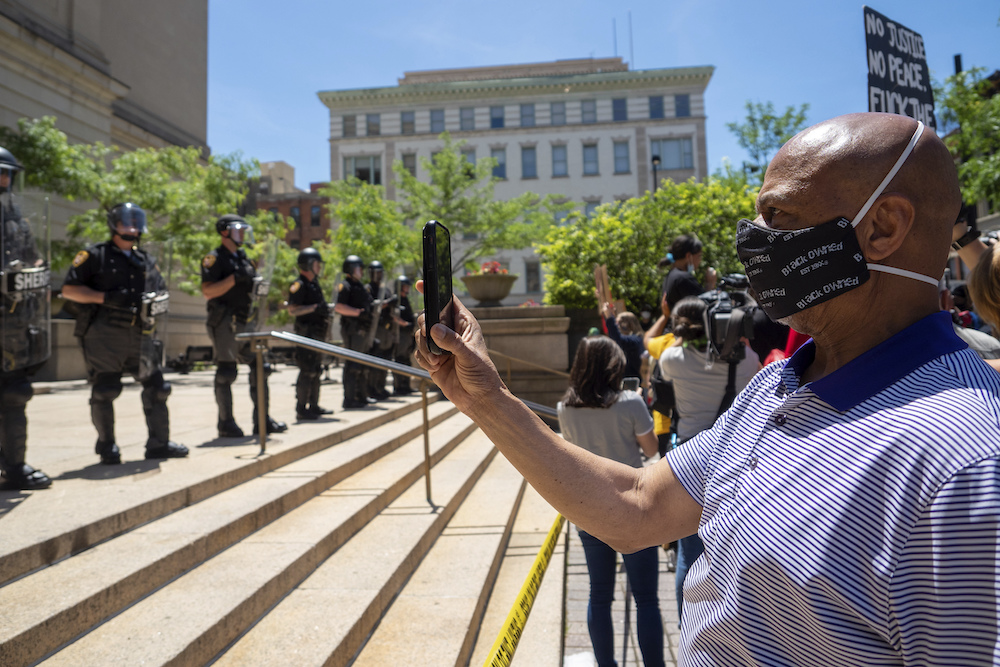 A man records Sheriff deputies with his cell phone as demonstrators rally at the Hamilton County Courthouse to protest the murder of George Floyd, Monday, June 1, 2020, in Cincinnati, Ohio.