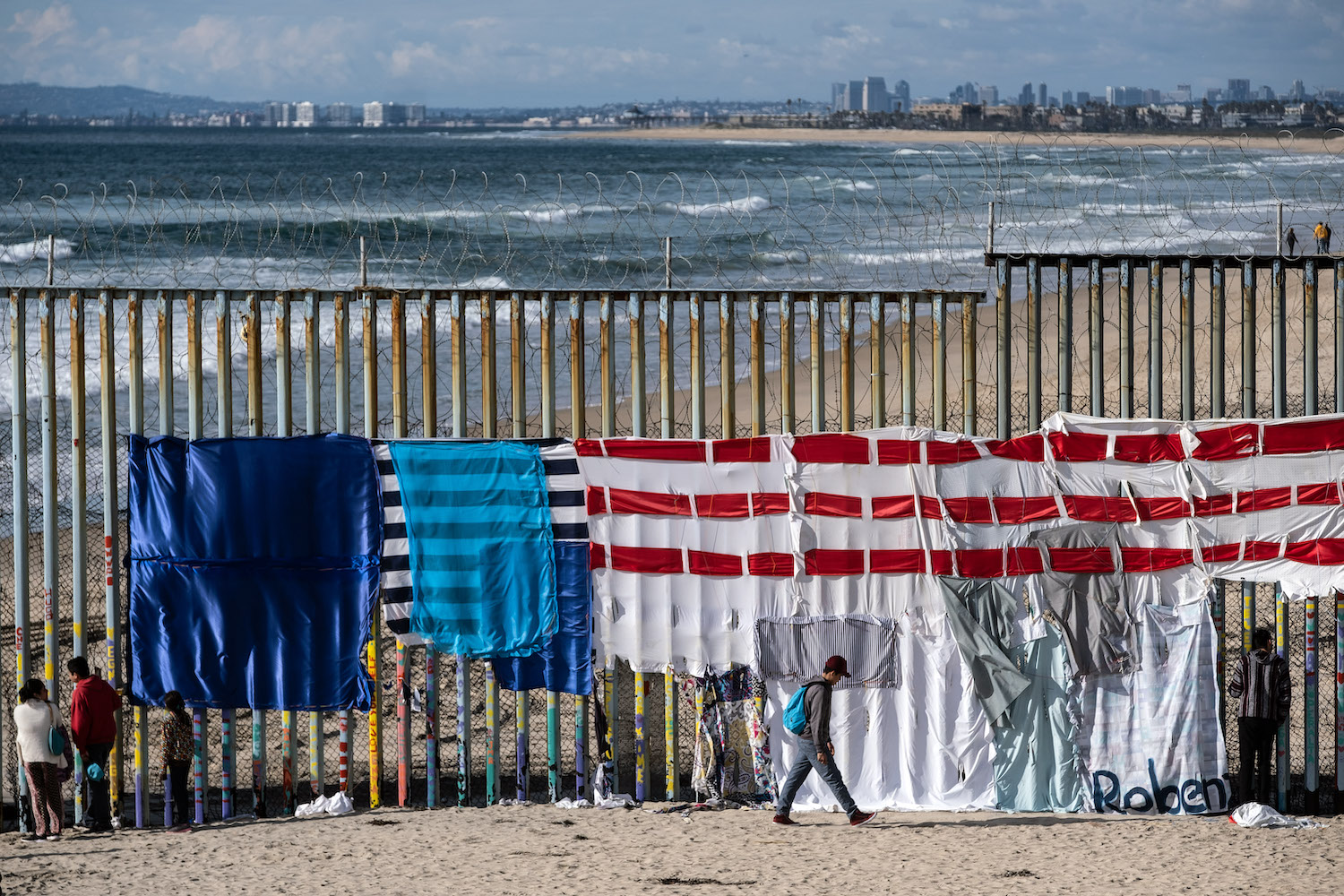 A collection of cloths representing the U.S. flag on a portion of the U.S.-Mexico border wall.