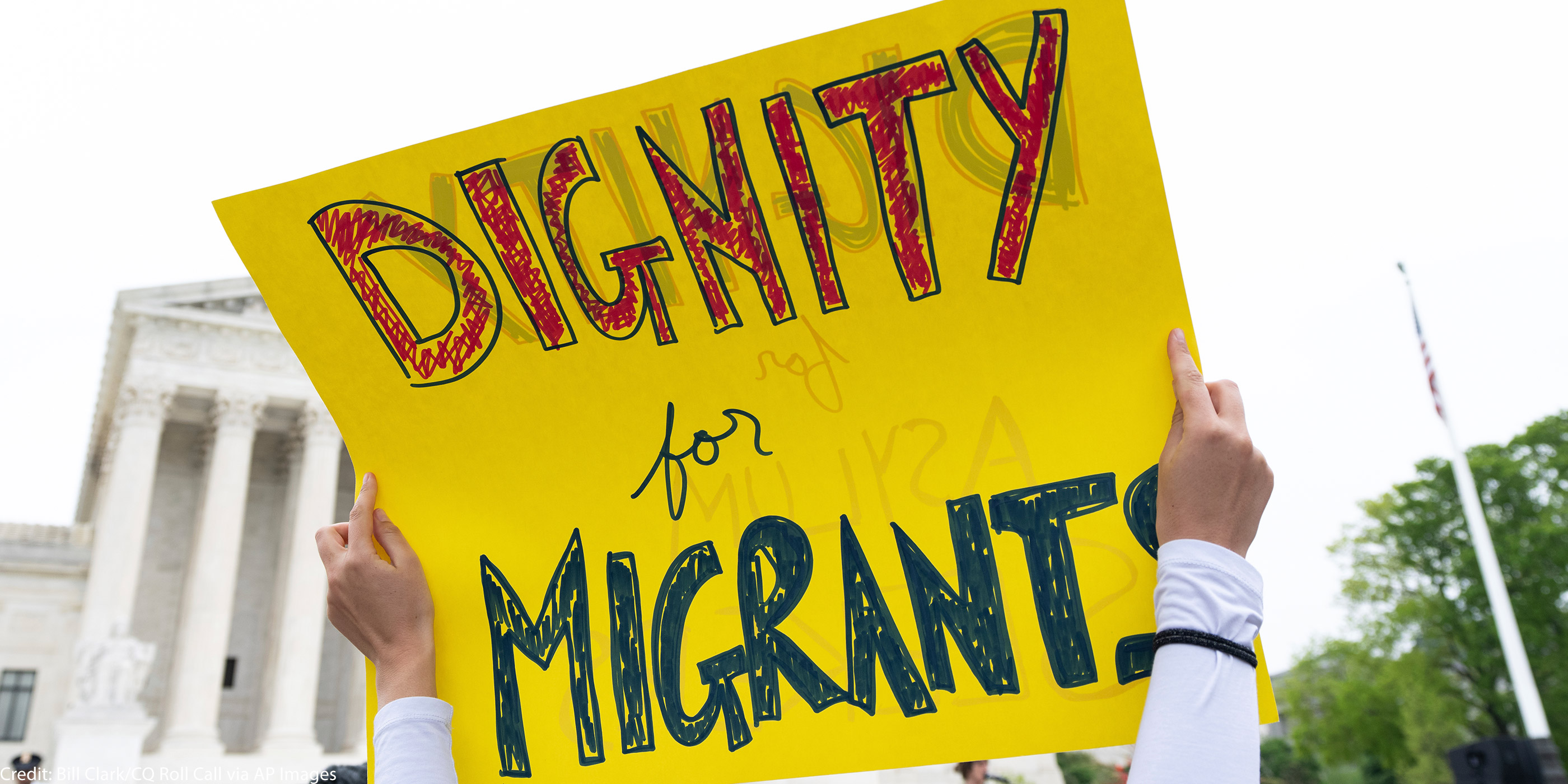 A sign reading "Dignity for Migrants."