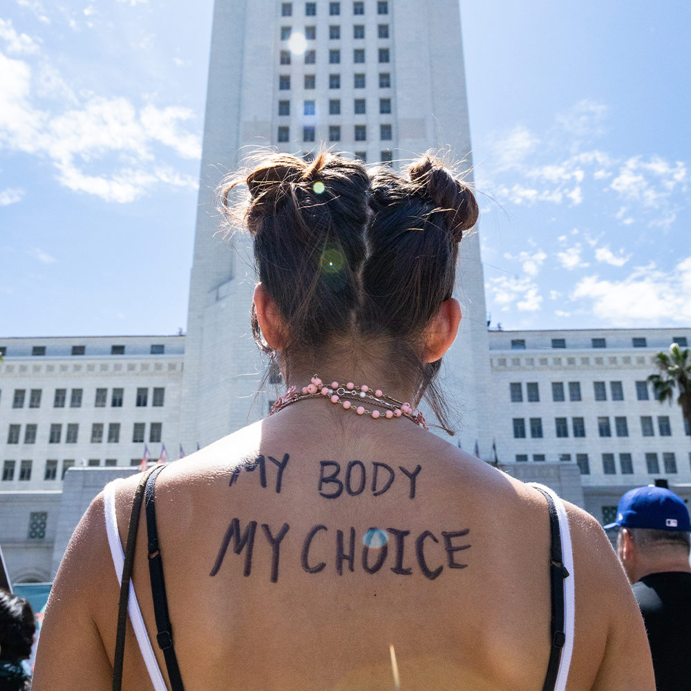 A protester uses her body as a canvas to elucidate her view in front of Los Angeles' City Hall.