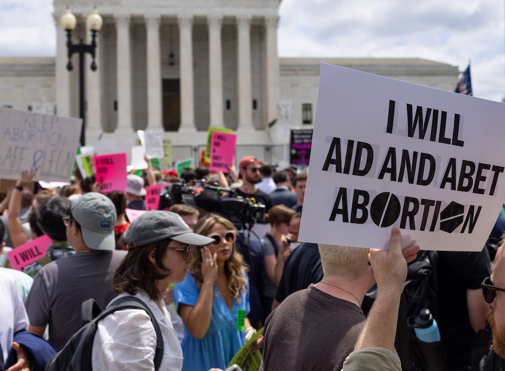 A demonstrator holding a sign that says "I Will Aid and Abet Abortion."
