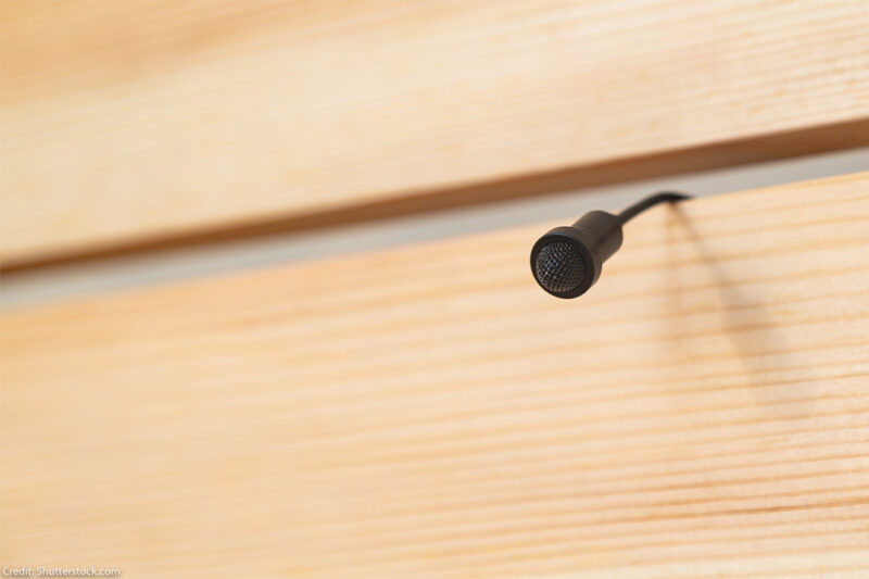 Hidden microphone coming between wooden slats on wall.