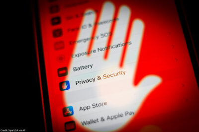 A cellphone screen with its privacy and security settings covered by a transparent hand with a red background.