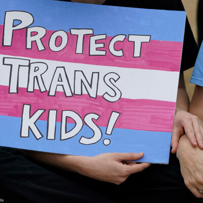 A protest sign reading "Protect Trans Kids."