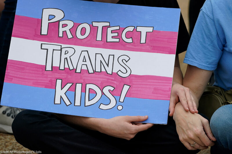 A protest sign reading "Protect Trans Kids."