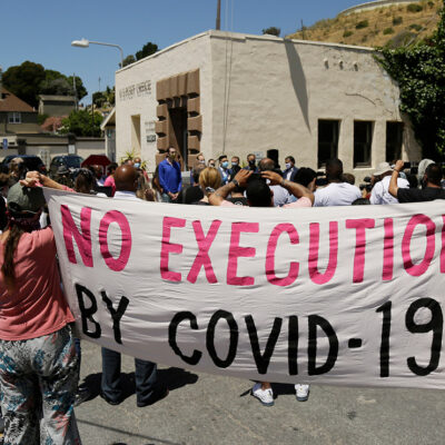 People hold up a banner saying "No Execution by Covid-19."