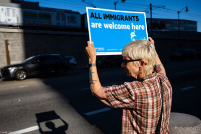 Protester holds a sign that says All Immigrants are Welcome Here.