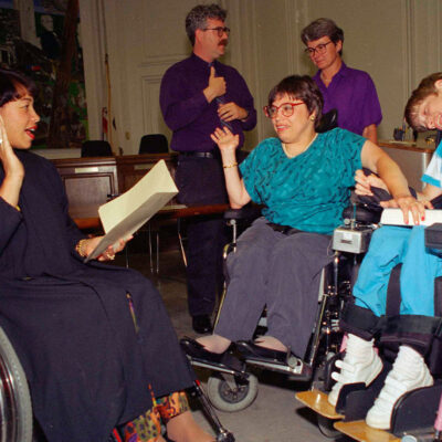 Judy Heumann, center wheelchair, is sworn in as U.S. Assistant Secretary for Special Education and Rehabilitative Service by Judge Gail Bereola, left, on June 29, 1993. Standing at left is Berkeley Mayor Loni Hancock with sign language interpreter Joseph Quinn, and Julie Weissman, right.