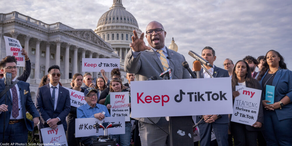 An individual at a podium in front of a crowd, with a sign that says "Keep TikTok."