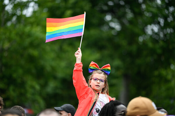 A little child waves a rainbow flag at a Pride March.