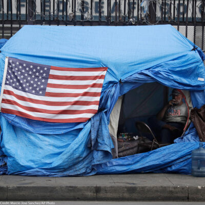 A man smokes inside a tent on skid row Friday, March 20, 2020, in Los Angeles.