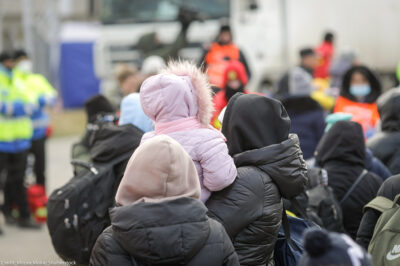 The back of a group of individuals, one holding a child with a hooded coat on.