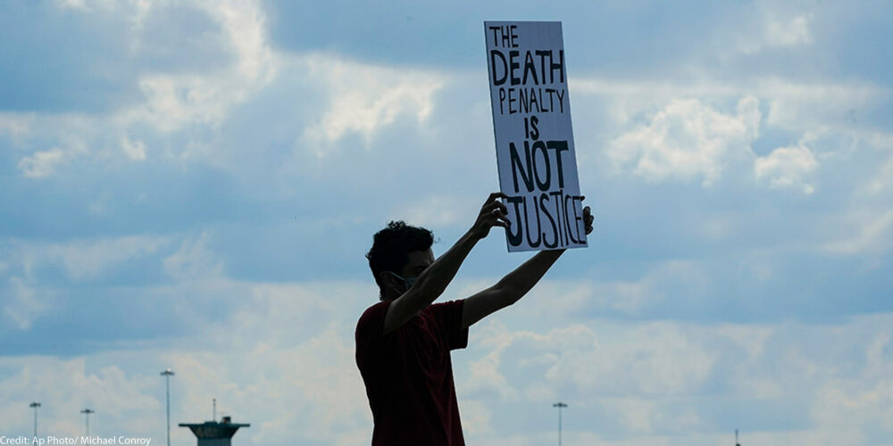 An individual holding a sign that says The Death Penalty is Not Justice.