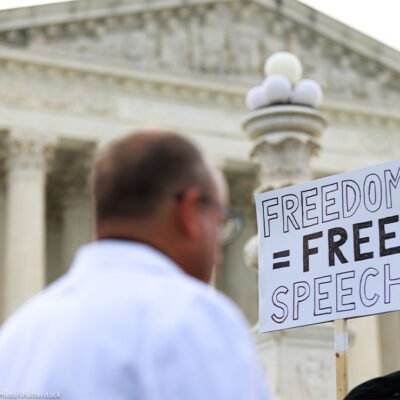 Free Speech supporters hold up a sign reading "FREEDOM = FREE SPEECH" outside the U.S. Supreme Court.