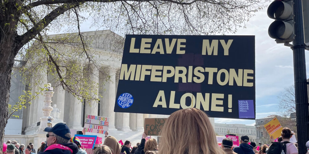 A demonstrator holding a sign that says "Leave My Mifepristone Alone."