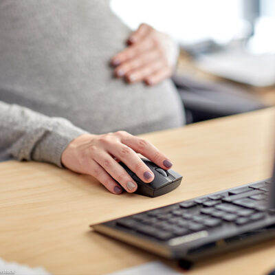 A pregnant worker on a computer at her desk.