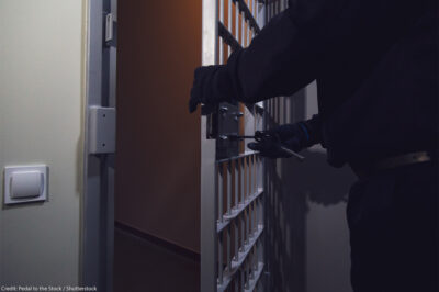 A cell door in a prison being locked by a gloved officer.